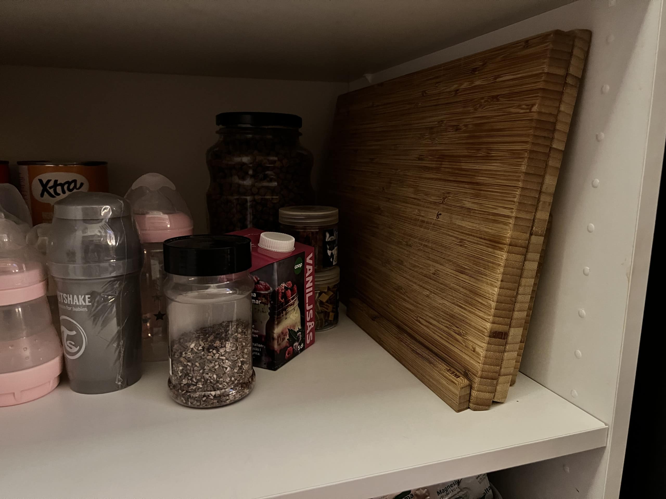 En översikt av en hylla med kryddburkar, en glasbehållare och ett skärbräda i trä, vilket ger en praktisk och organiserad känsla.