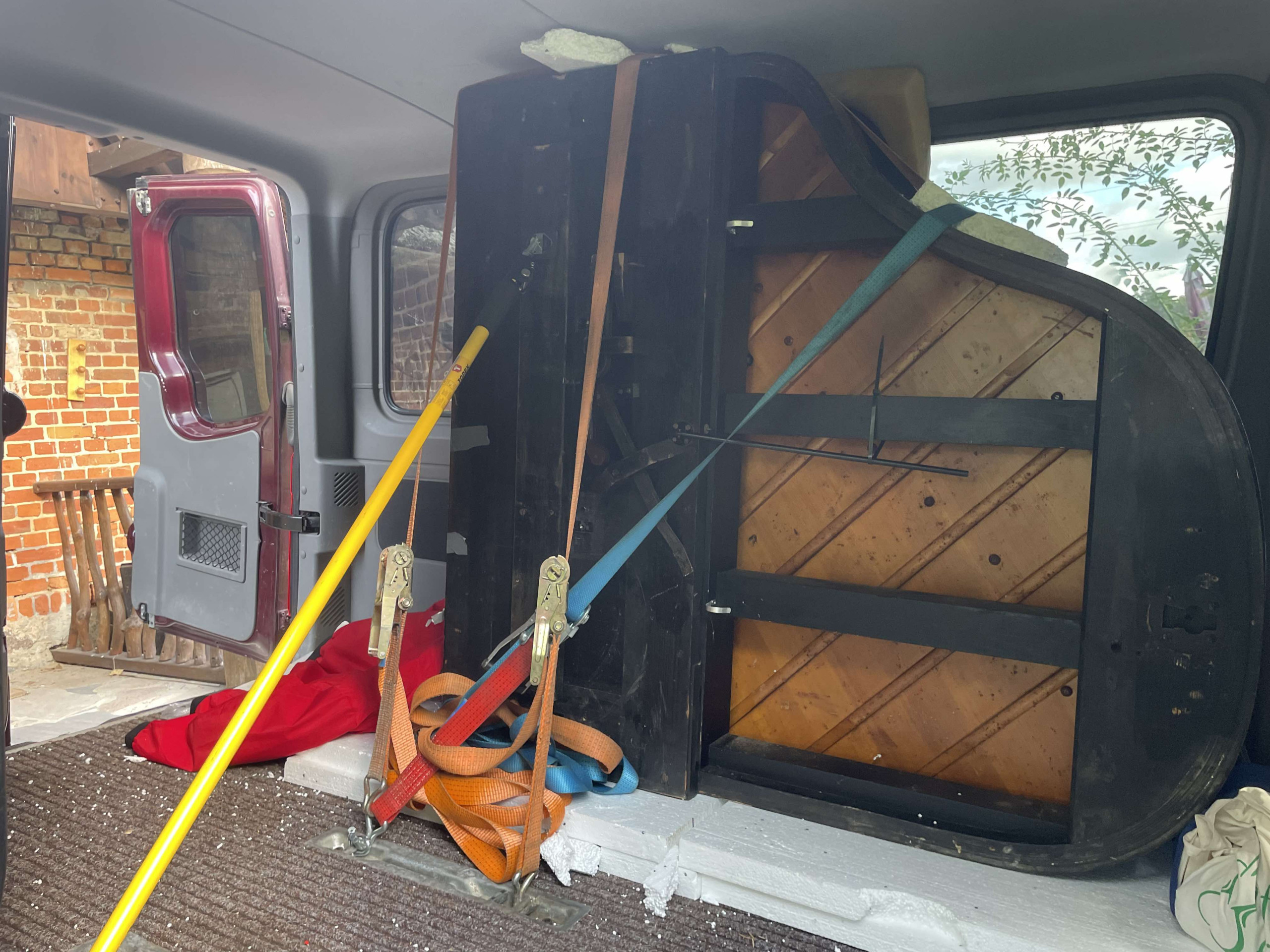 Ett piano säkrat i en bil, redo för transport. Perfekt för att ge nytt liv åt musiken i ditt hem.