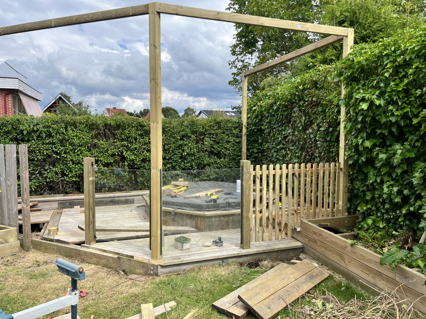 Badtunna omgiven av trästaket och glasparti, renovering pågår.