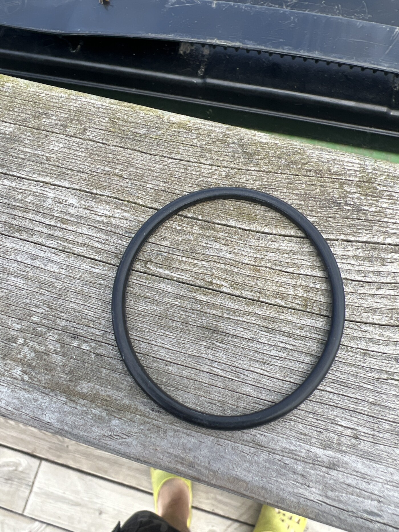 En svart gummiring ligger på en träyta, en del av badtunnans kopplingar för att åtgärda vattennivån.